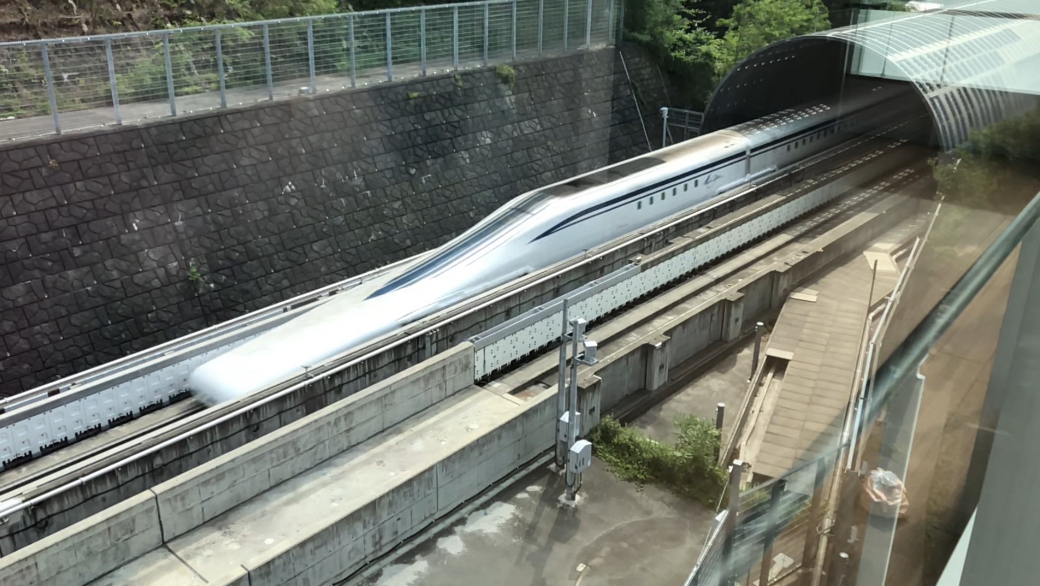 Photograph of the L0-series Shinkansen passing the Maglev Exhibition Centre on the Yamanashi Test Track