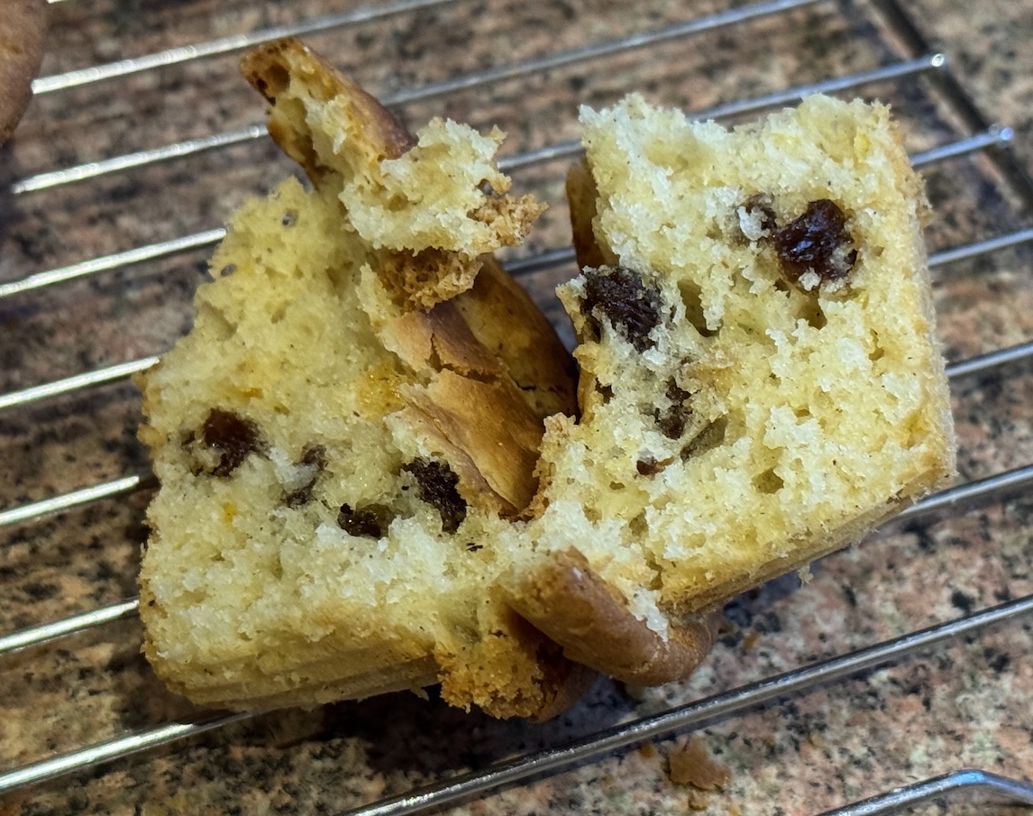 Photograph of a mini-panettone split vertically down the middle.
The crumb is good, with a pale yellow colour.
The top appears crunchy;
the sides less so.
The raisins are visible on the inside.